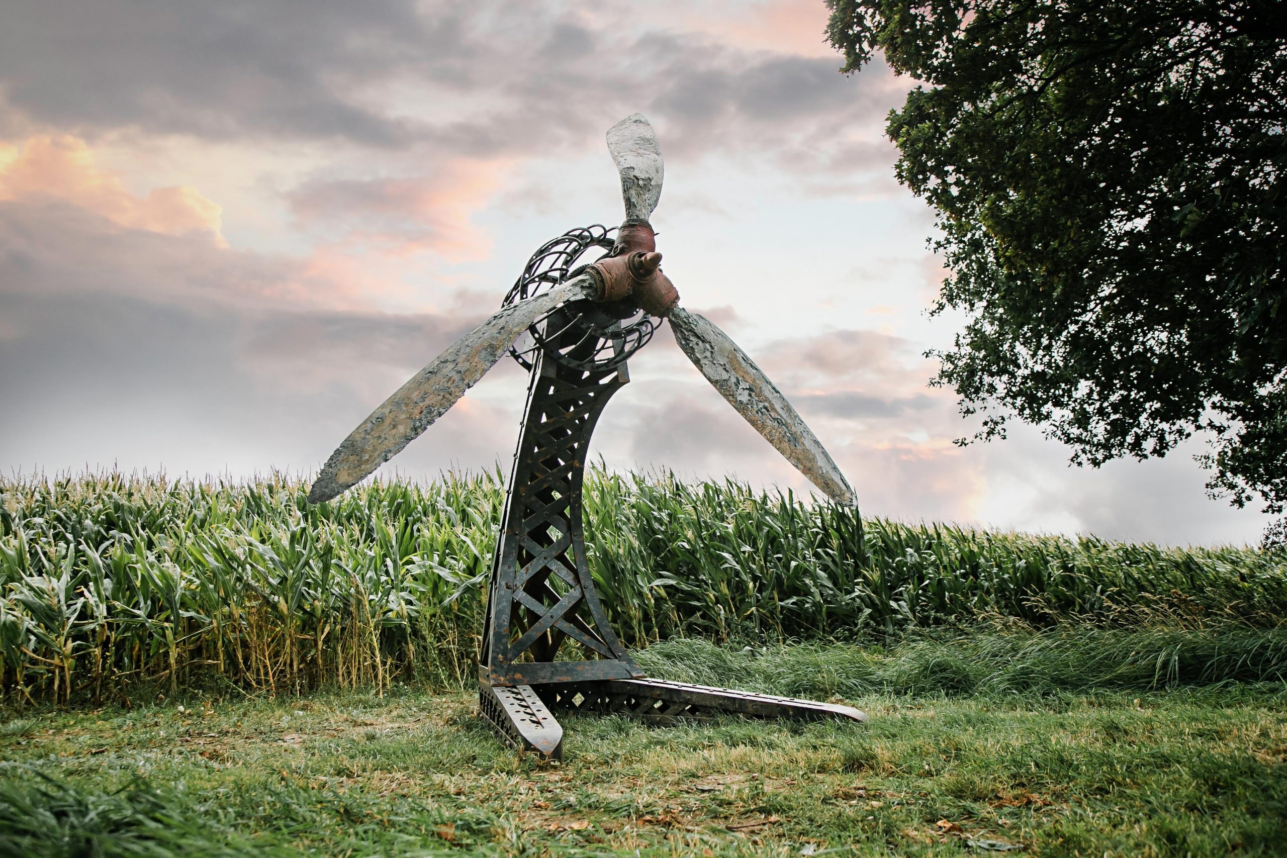 A architectural found object sculpture of a plane propeller mounted onto a metal frame.