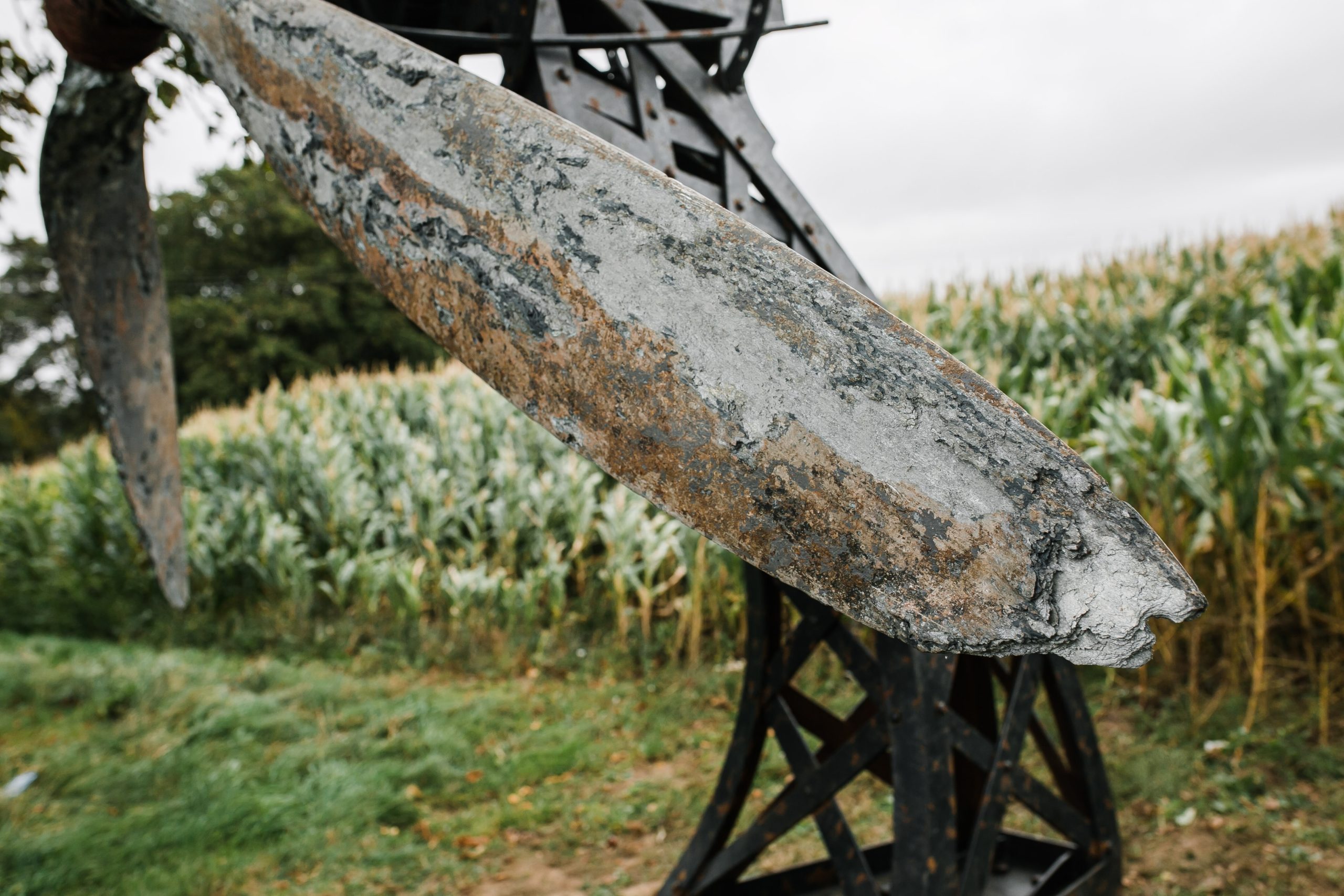 A architectural found object sculpture of a plane propeller mounted onto a metal frame.