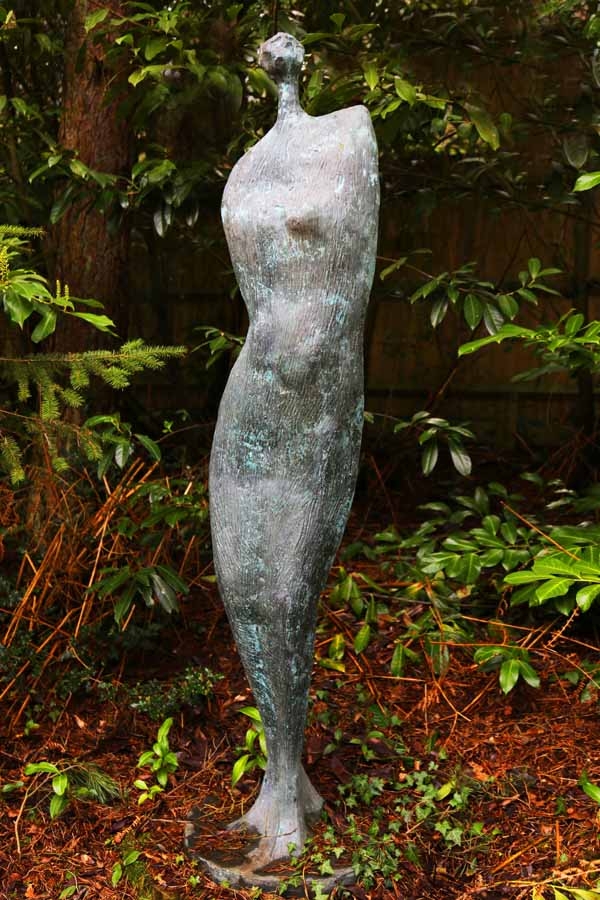 A abstract bronze sculpture of a figure wearing a long dress.
